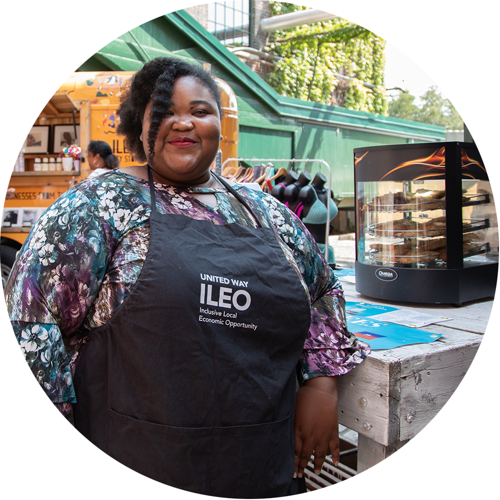 A women wearing an ILEO apron infront of her stroefront